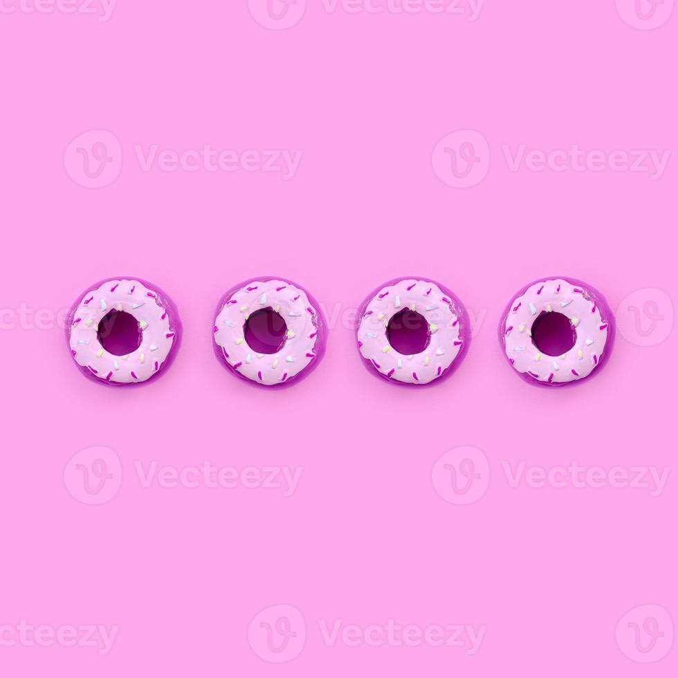 Many small plastic donuts lies on a pastel colorful background. Flat lay minimal pattern. Top view photo