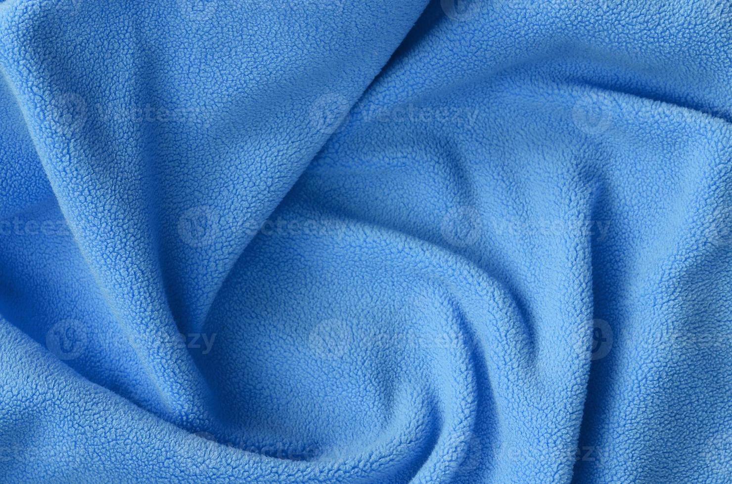 la manta de tejido polar azul peludo. un fondo de material polar de felpa suave azul claro con muchos pliegues en relieve foto