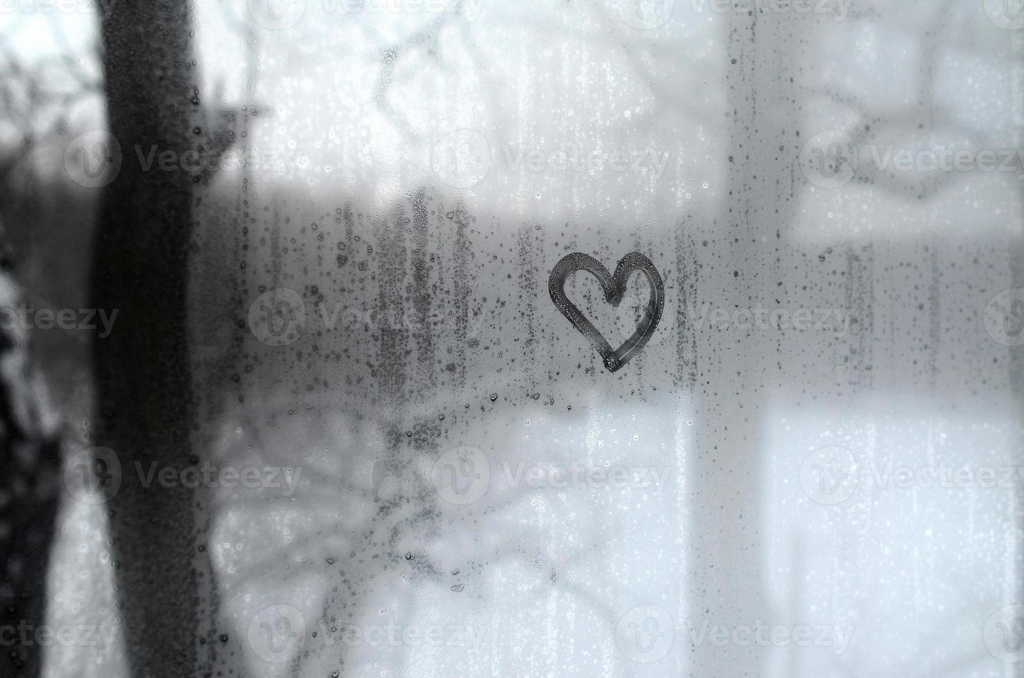 The heart is painted on the misted glass in winter photo