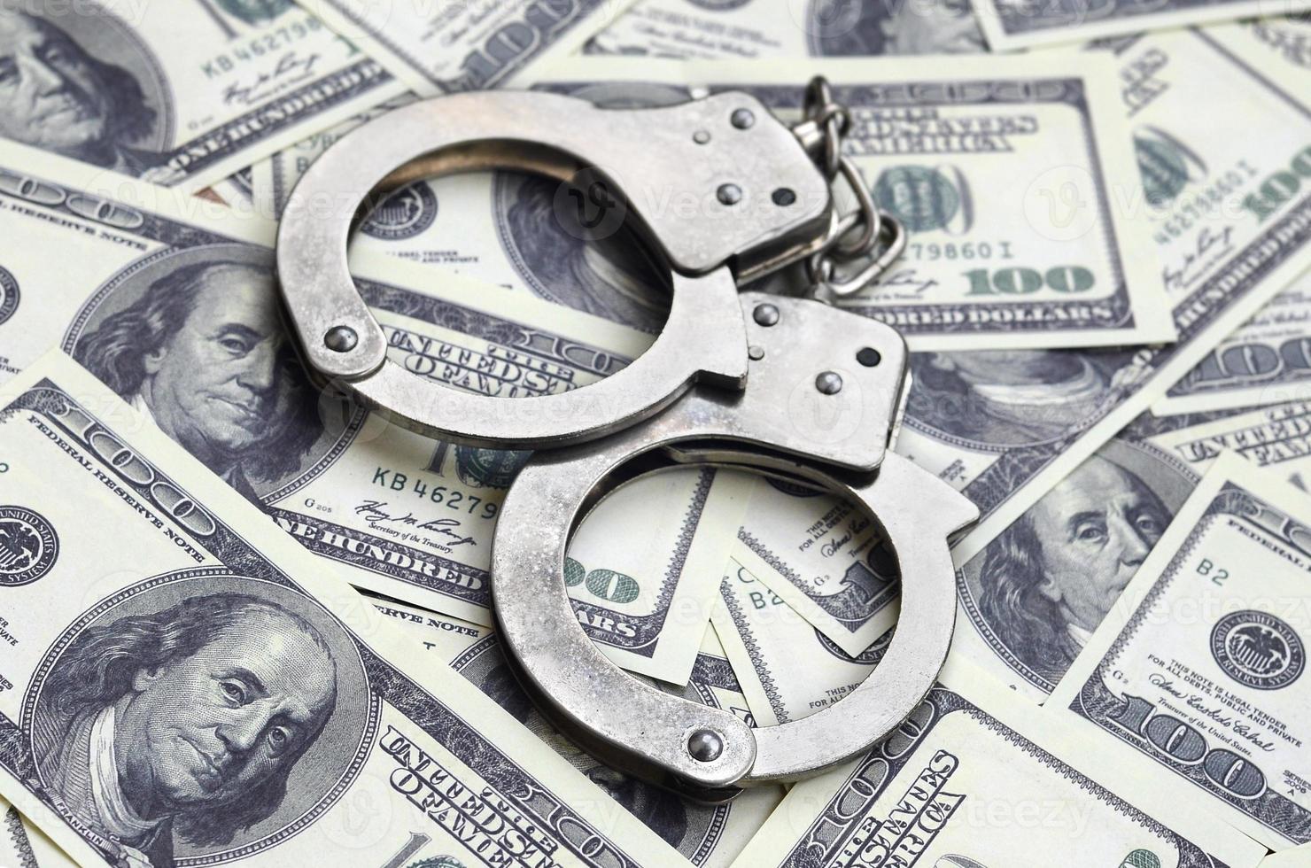 Police handcuffs lie on a lot of dollar bills. The concept of illegal possession of money, illegal transactions with US dollars. Economic Crime photo