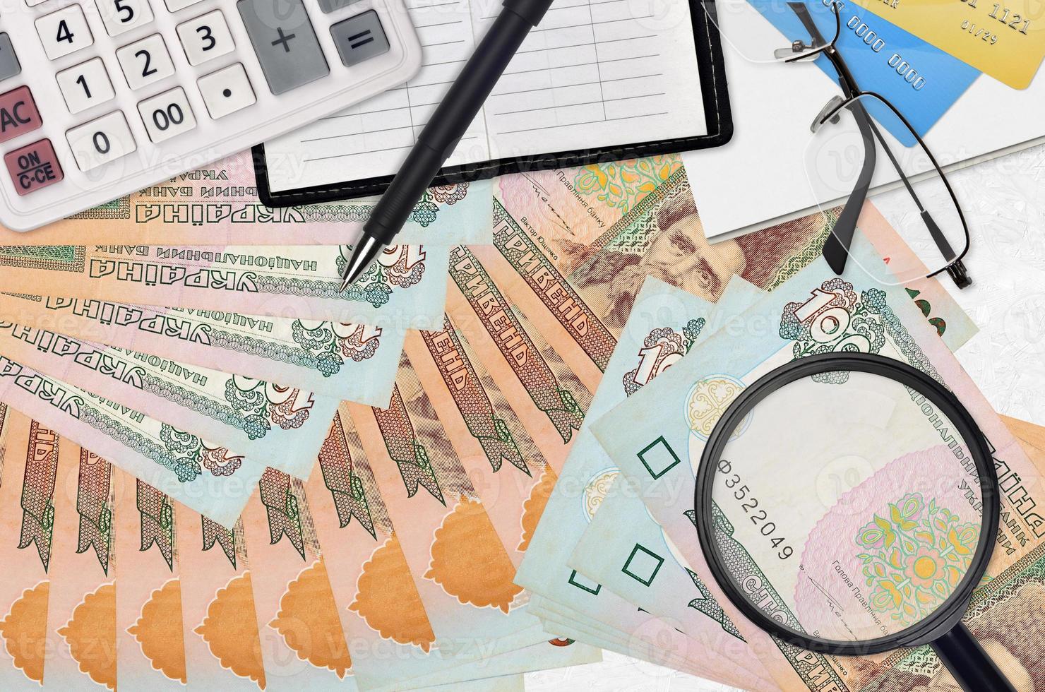 100 Ukrainian hryvnias bills and calculator with glasses and pen. Tax payment season concept or investment solutions. Searching a job with high salary photo