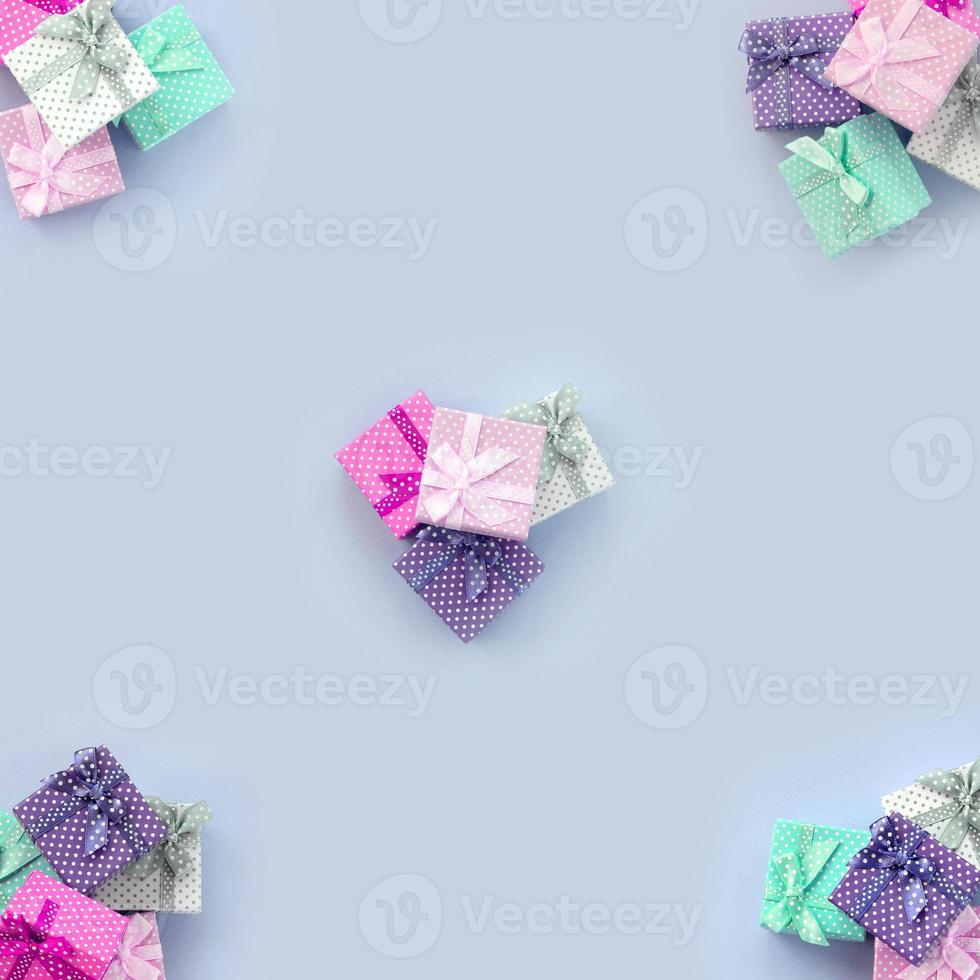 Piles of a small colored gift boxes with ribbons lies on a violet background photo