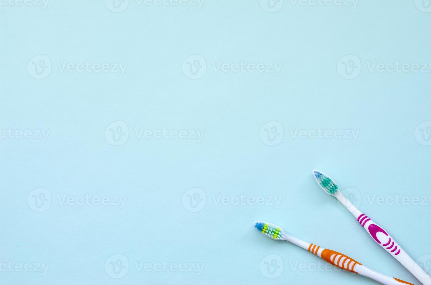 dos cepillos de dientes yacen sobre un fondo azul pastel. vista superior, endecha plana. concepto mínimo foto