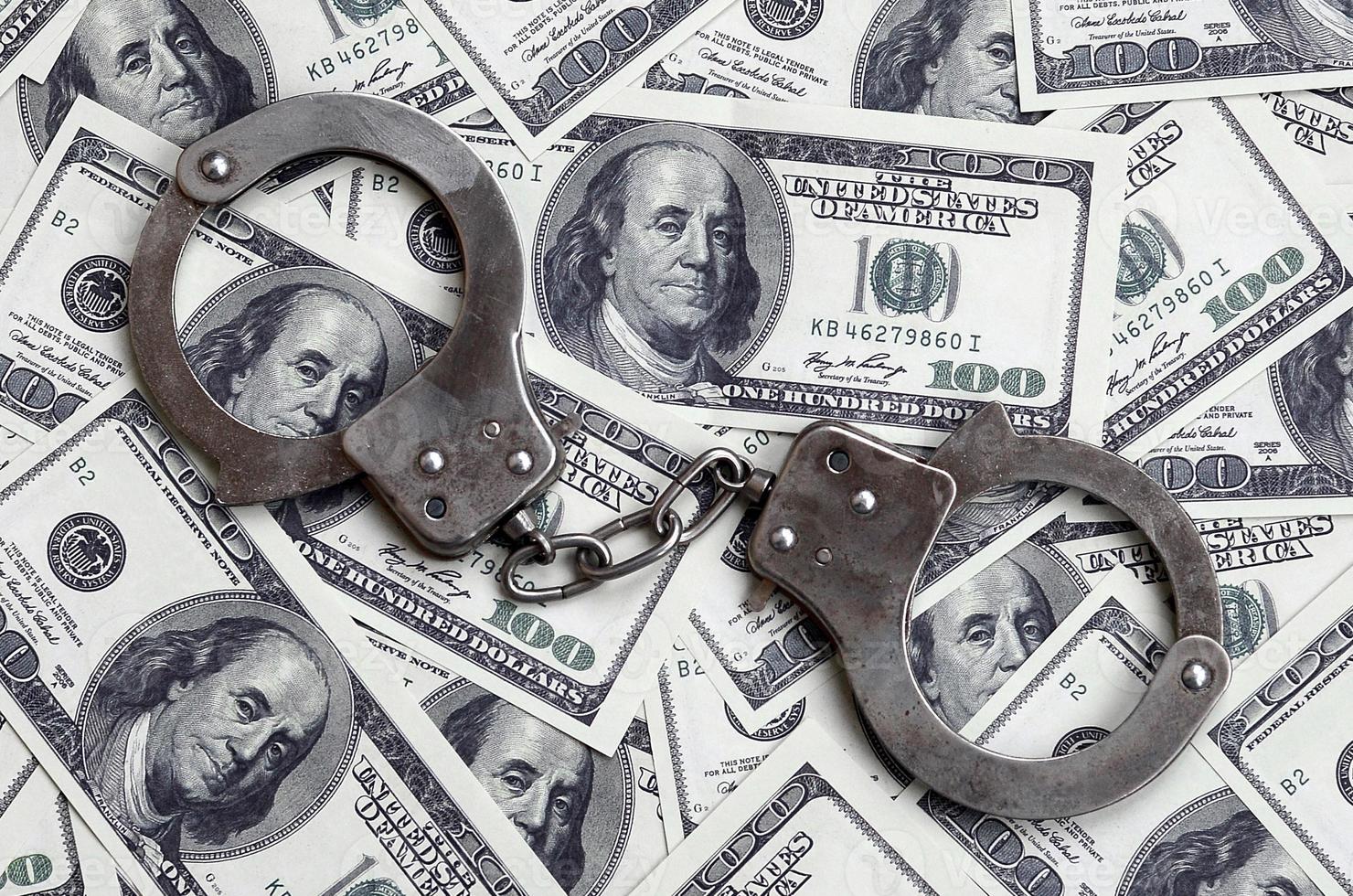 Police handcuffs lie on a lot of dollar bills. The concept of illegal possession of money, illegal transactions with US dollars. Economic Crime photo