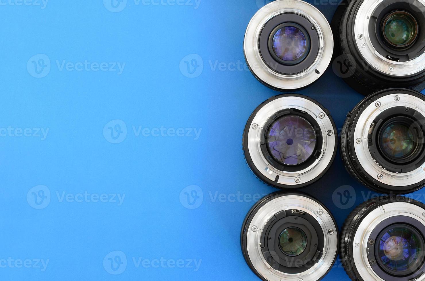 Several photographic lenses lie on a bright blue background. Space for text photo