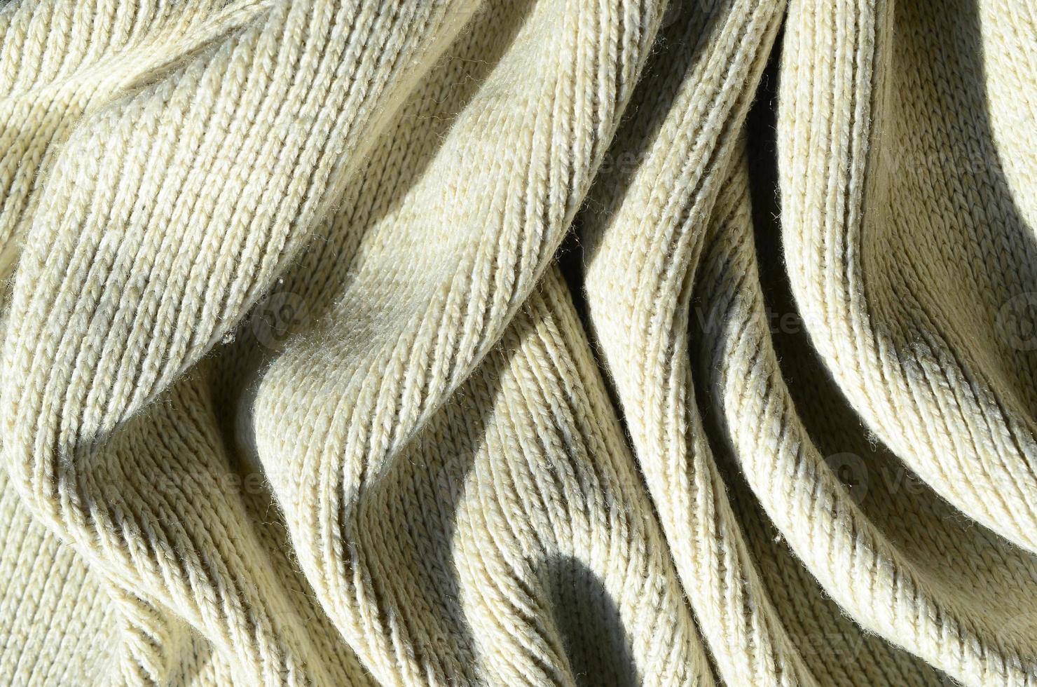 Fabric texture of a soft yellow knitted sweater. Macro image of the structure of bindings in yarns photo