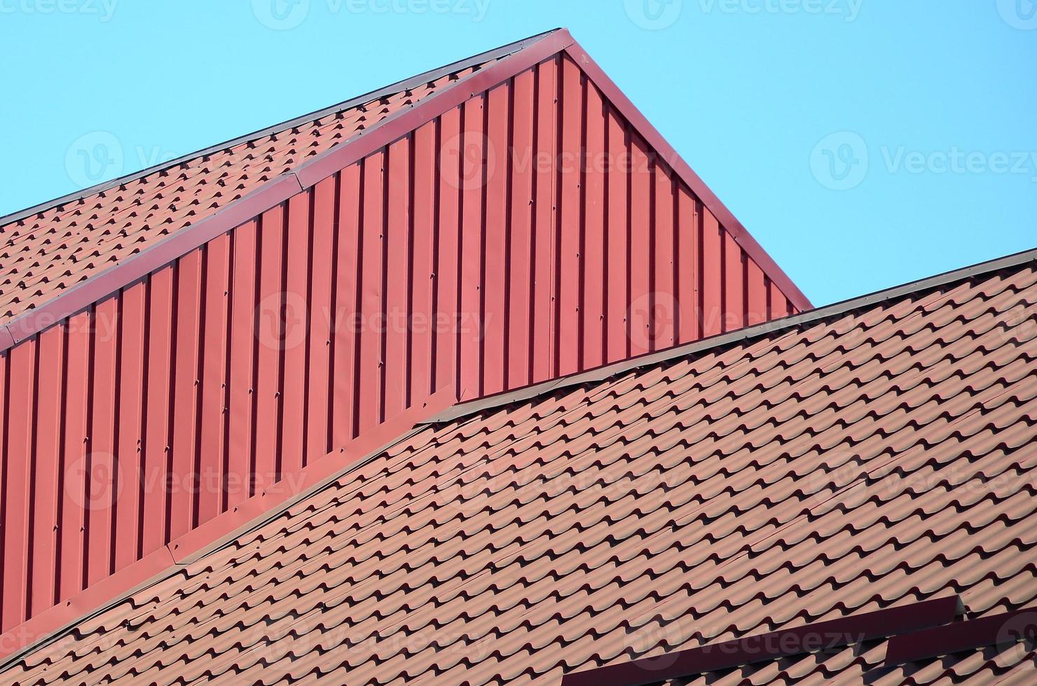 A fragment of a roof from a metal tile of dark red color. Quality Roofing photo