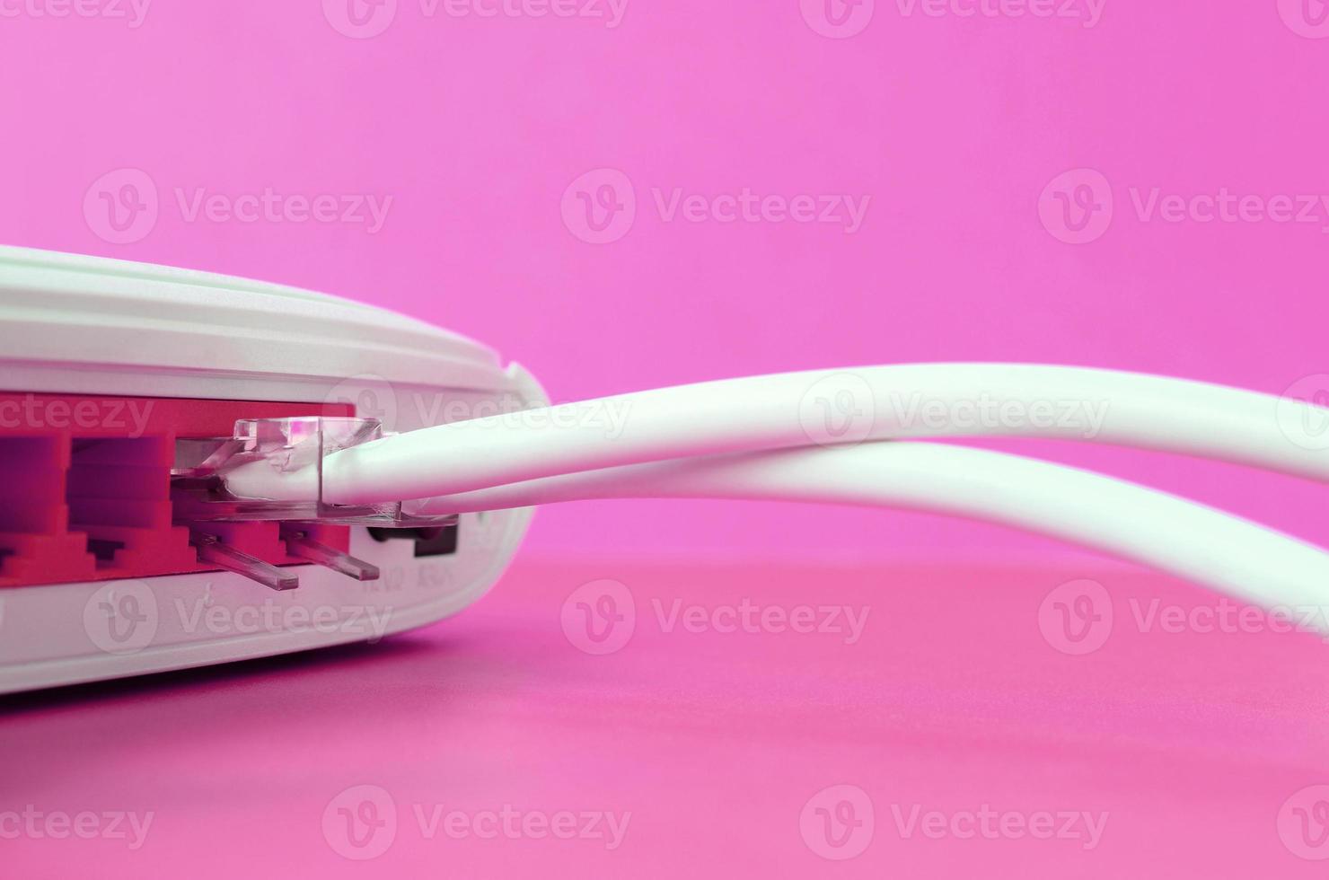 The Internet cable plugs are connected to the Internet router, which lies on a bright pink background. Items required for Internet photo