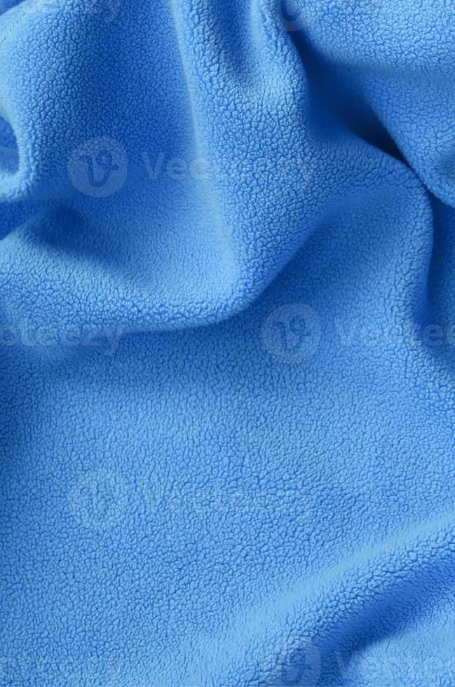 The blanket of furry blue fleece fabric. A background of light blue soft plush fleece material with a lot of relief folds photo