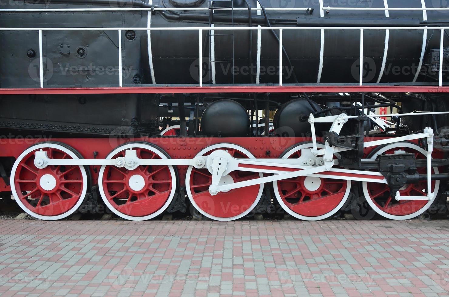 Wheels of the old black steam locomotive of Soviet times. The side of the locomotive with elements of the rotating technology of old trains photo