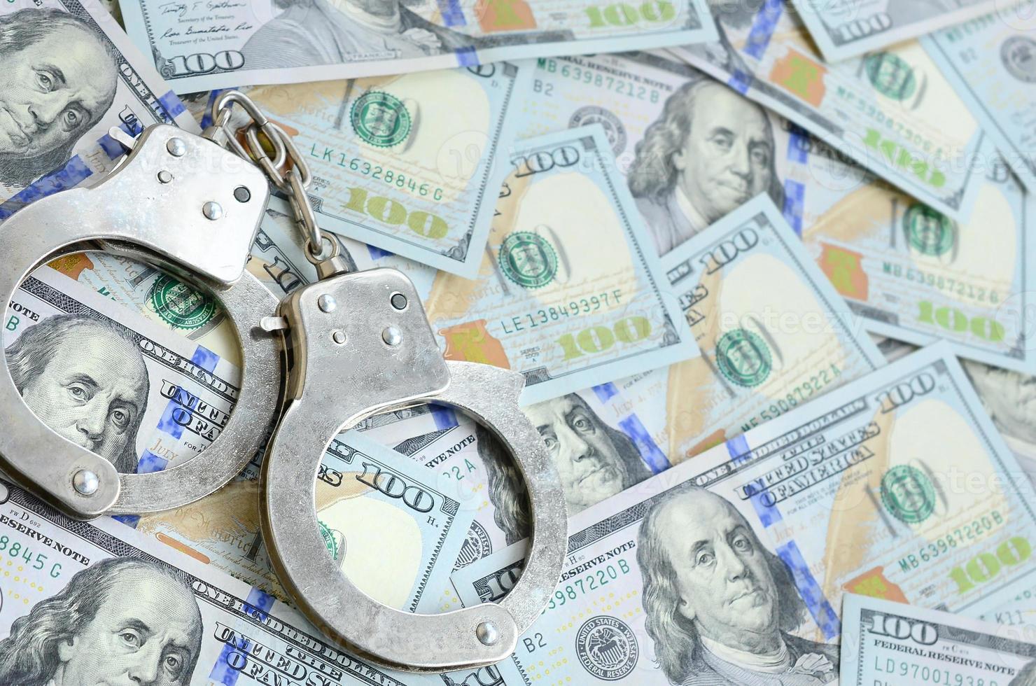 Silver police handcuffs lies on a many dollar bills photo