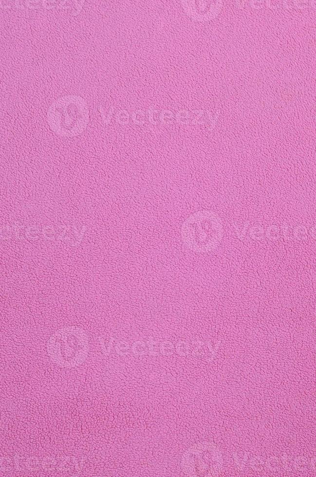 The blanket of furry pink fleece fabric. A background texture of light pink soft plush fleece material photo