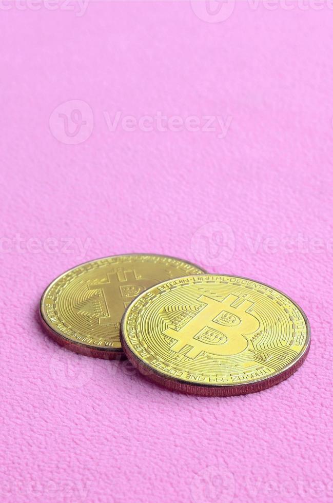 Two golden bitcoins lies on a blanket made of soft and fluffy light pink fleece fabric. Physical visualization of virtual crypto currency photo