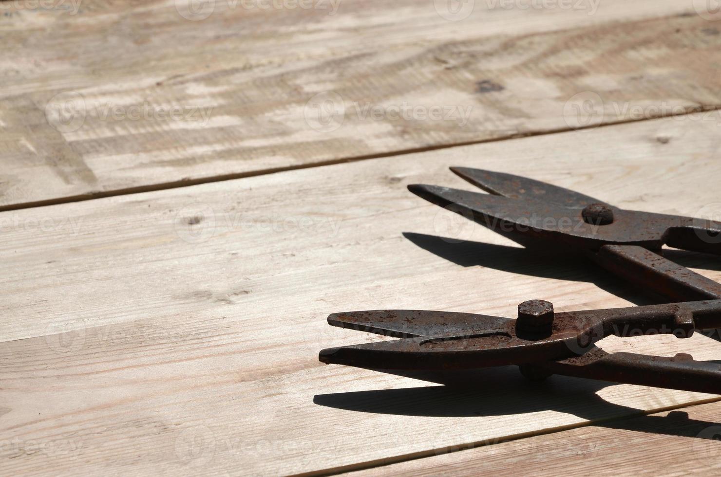 A few rusty scissors for metal lies on a wooden table in a workshop photo