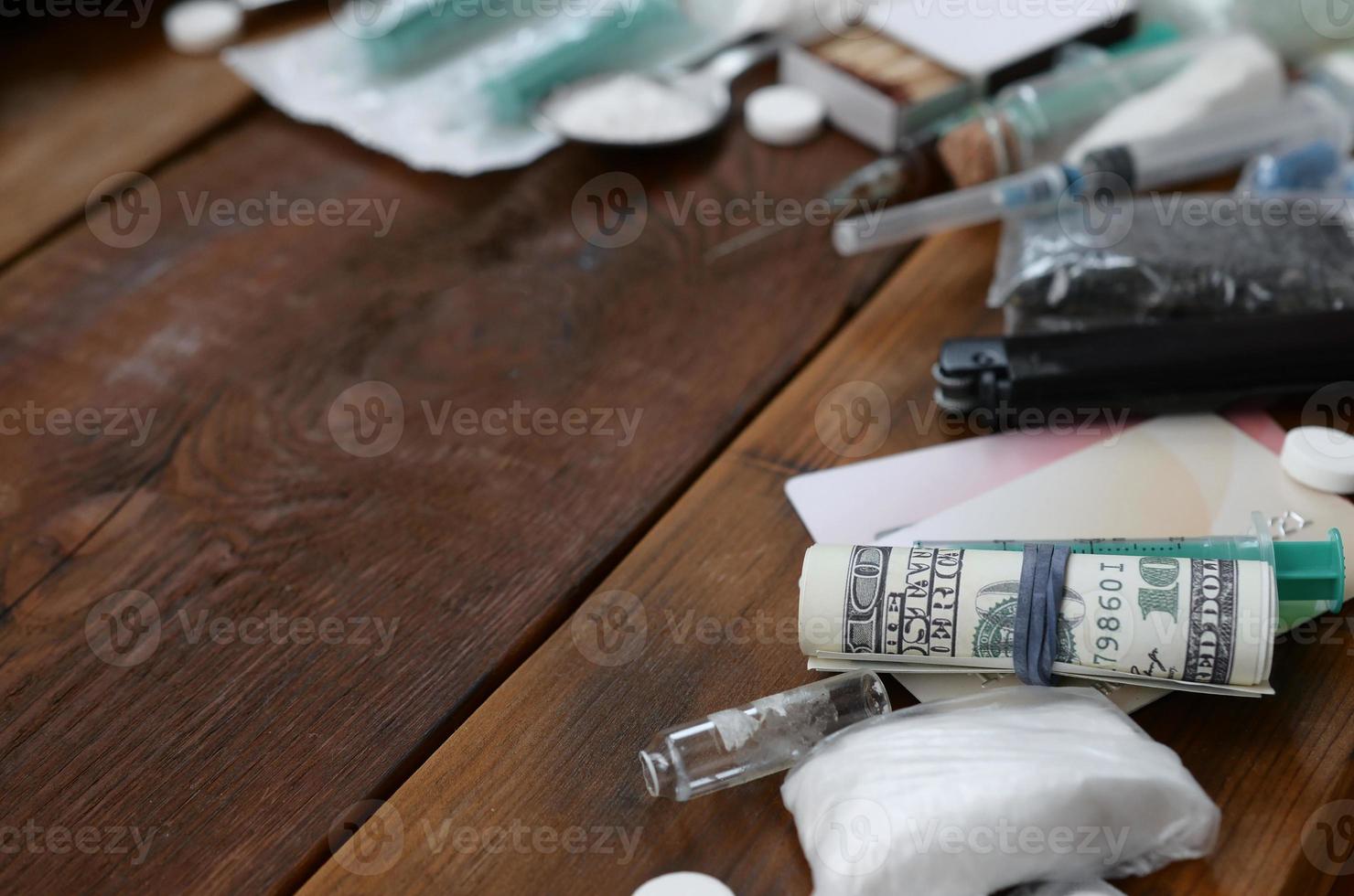 muchas sustancias estupefacientes y dispositivos para la preparación de drogas yacen sobre una vieja mesa de madera foto