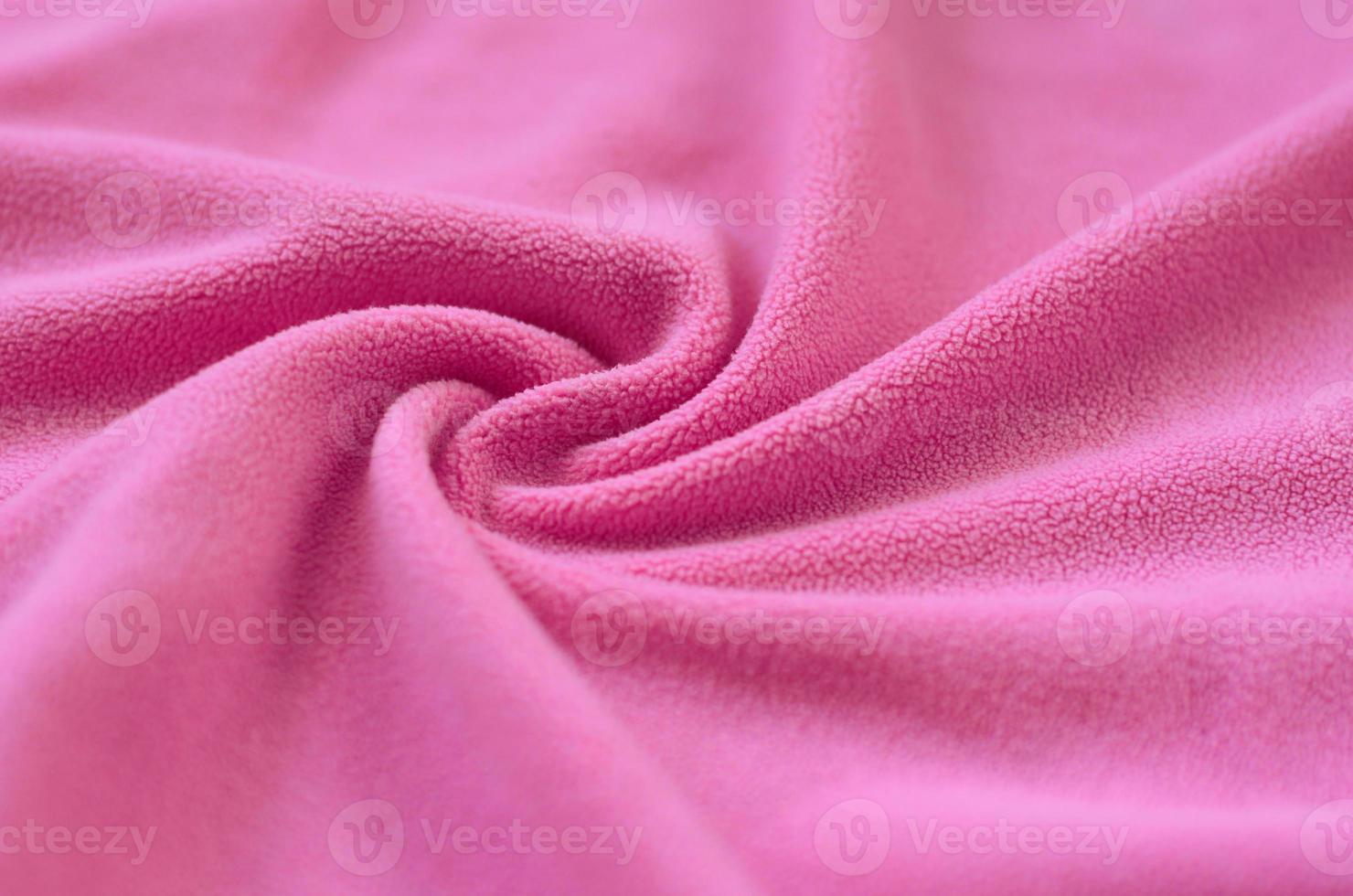 The blanket of furry pink fleece fabric. A background of light pink soft plush fleece material with a lot of relief folds photo