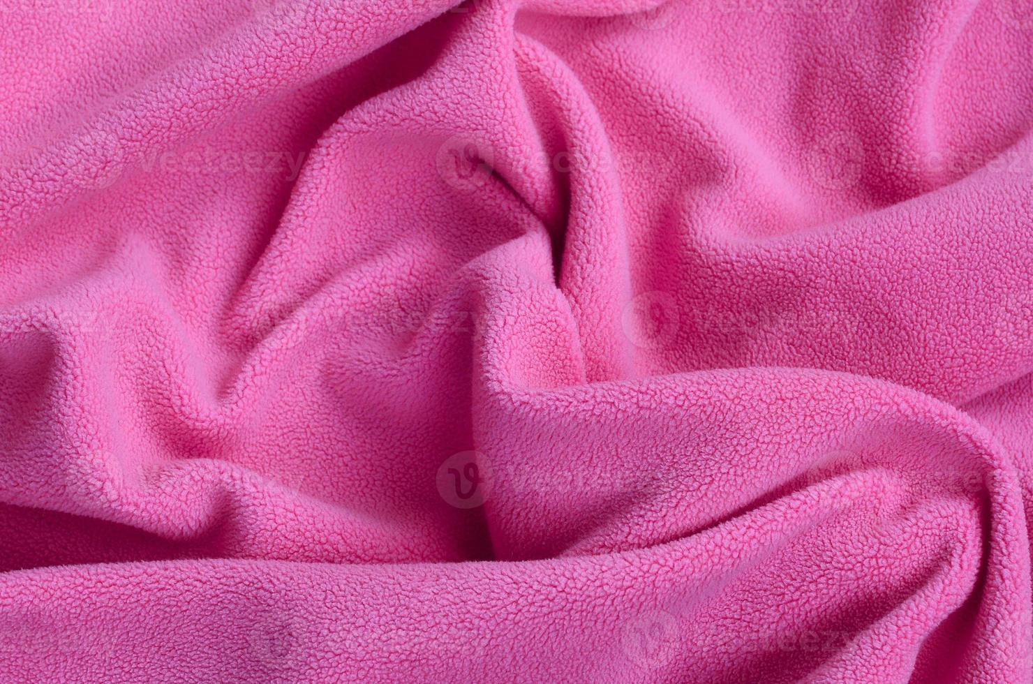 The blanket of furry pink fleece fabric. A background of light pink soft plush fleece material with a lot of relief folds photo