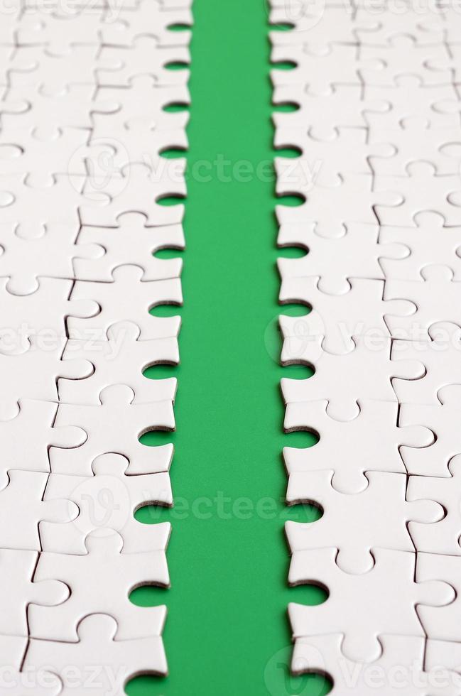 The green path is laid on the platform of a white folded jigsaw puzzle. Texture image with copy space for text photo
