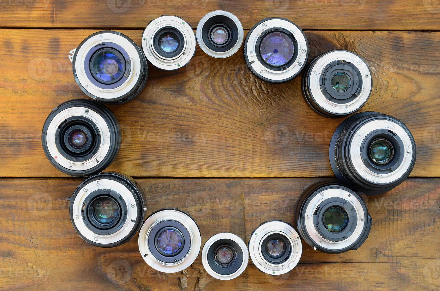 Several photographic lenses lie on a brown wooden background. Space for text photo