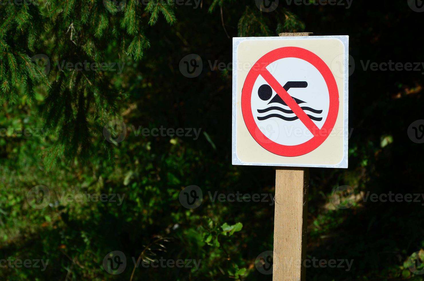 A pillar with a sign denoting a ban on swimming. The sign shows a crossed-out floating person photo