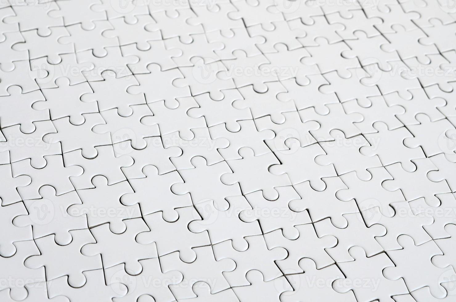 Close up of a white jigsaw puzzle in assembled state in perspective. Many components of a large whole mosaic are united photo