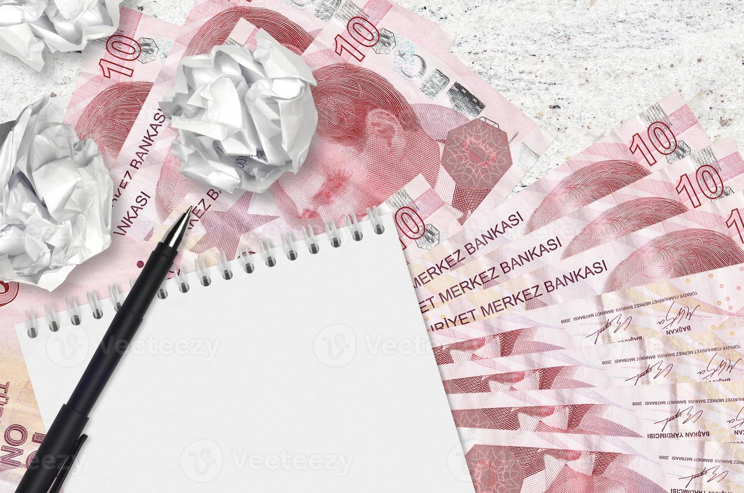 10 Turkish liras bills and balls of crumpled paper with blank notepad. Bad ideas or less of inspiration concept. Searching ideas for investment photo