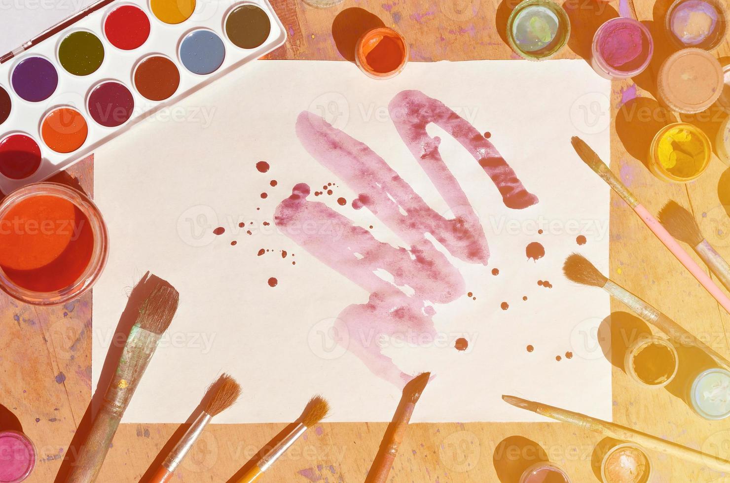 Still life with painted sheet of paper and jars of watercolor and gouache paint photo