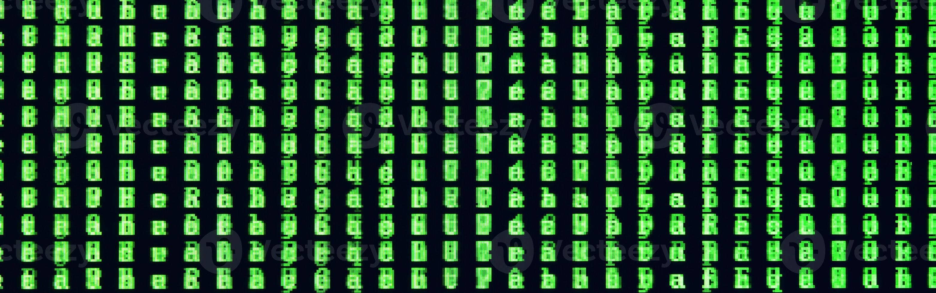 Macro shot of a glitch on the monitor of an office computer. The concept of introducing a virus into a personal data keeper. Stream of random green symbols on a black background photo