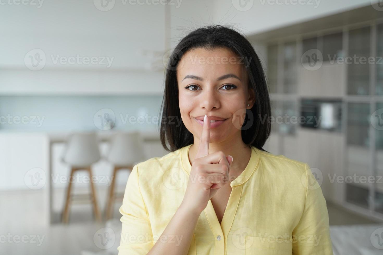 Female makes silence gesture keeping finger at lips asks be quiet at home, sharing secret about sale photo