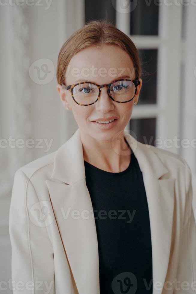 Pretty businesswoman in glasses and office jacket looking at camera. Eyeglass store advertising photo