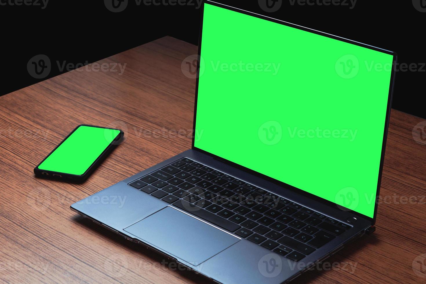 Mockup image with green screen on computer and smartphone on wood desk. Background for advertising text. Space for design. photo