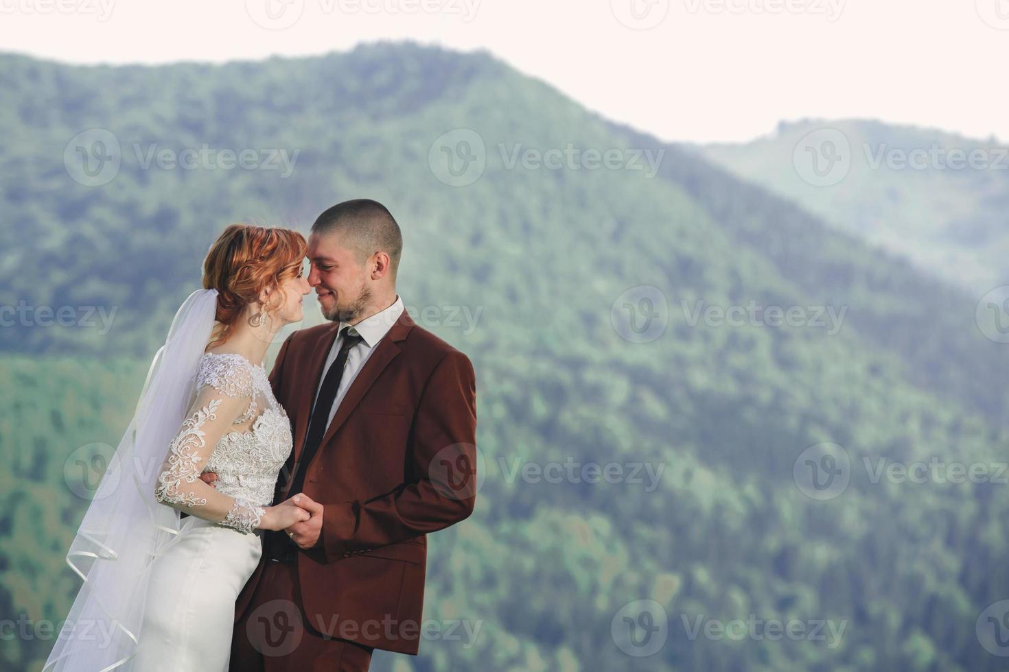 happy stylish bride and groom running and having fun in mountains on summer sunny day. gorgeous newlywed couple laughing, true feelings. emotional romantic moment. photo