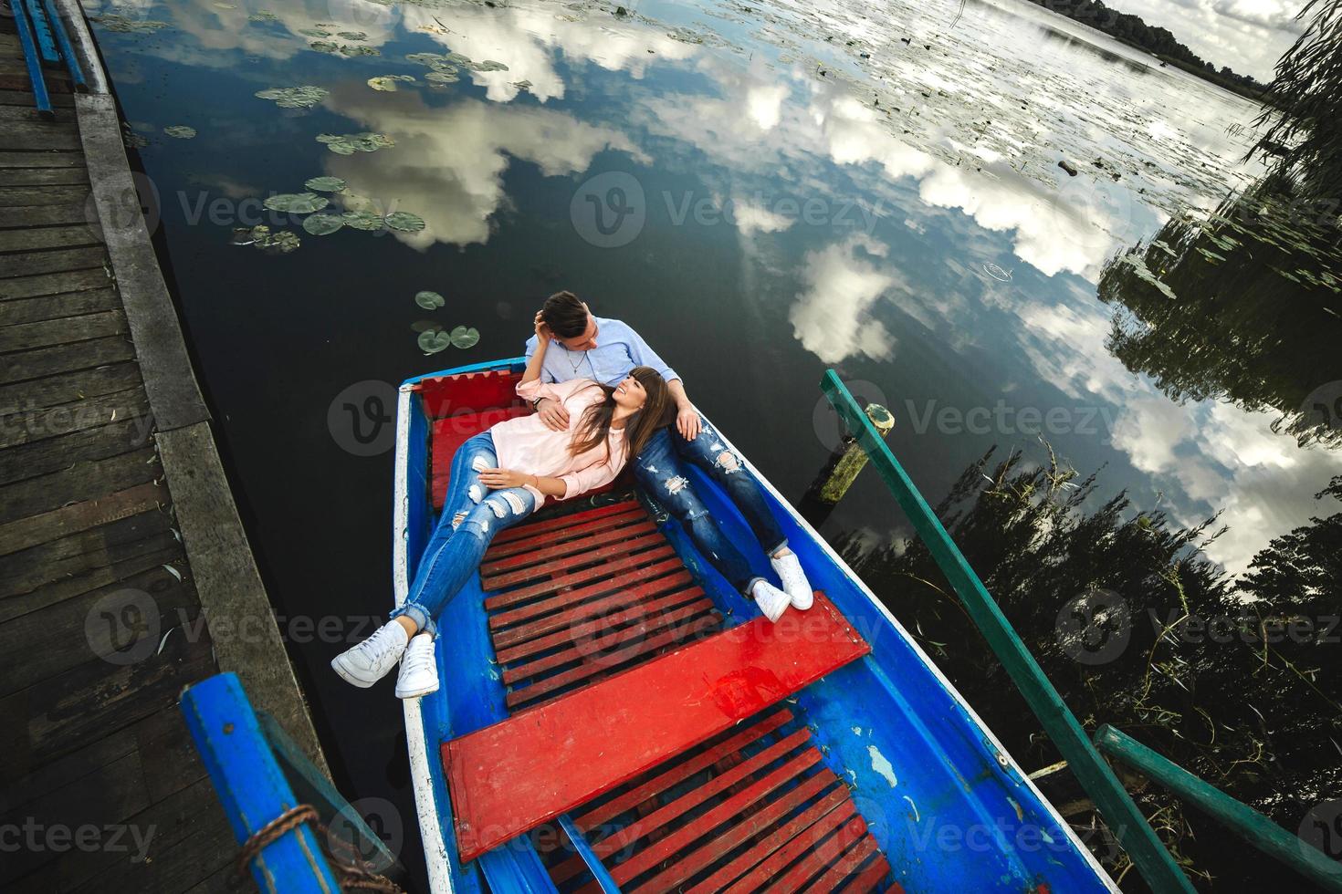 A couple riding a blue boat on a lake. romance. emotional couple. funny and in love photo