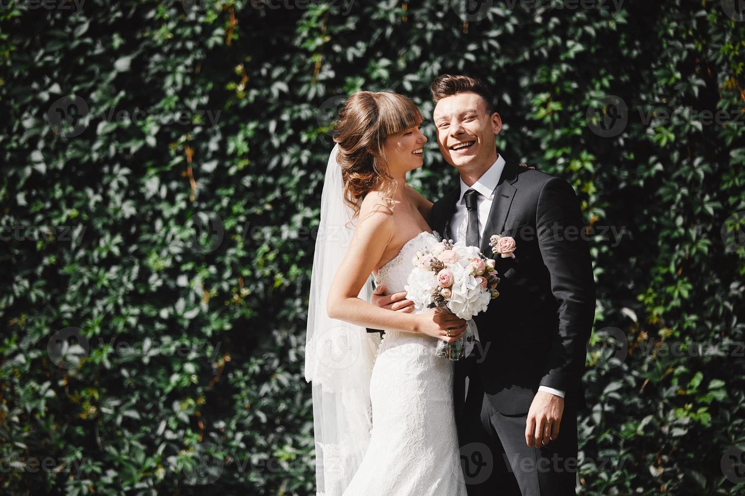 Closeup Portrait of wedding bride and groom with bouquet posing. Bridal couple, Happy Newlywed woman and man hugging. Bride and groom photo