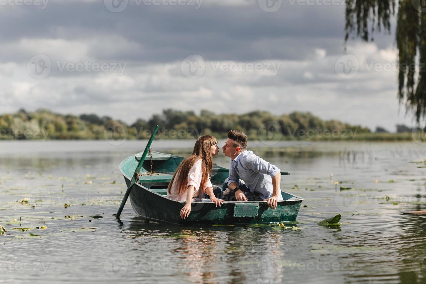 simplemente relajarse. hermosa joven pareja disfrutando de una cita romántica mientras rema en un bote. pareja amorosa descansando sobre un lago mientras viajaba en un bote verde. romance. foto