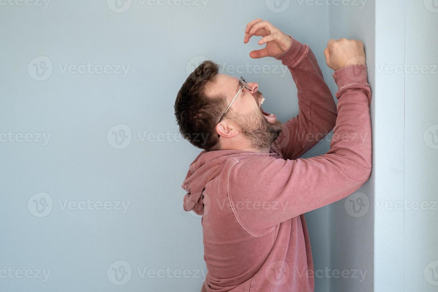 el hombre está molesto y desesperado, grita o llora en voz alta, parado contra la pared. copie el espacio foto