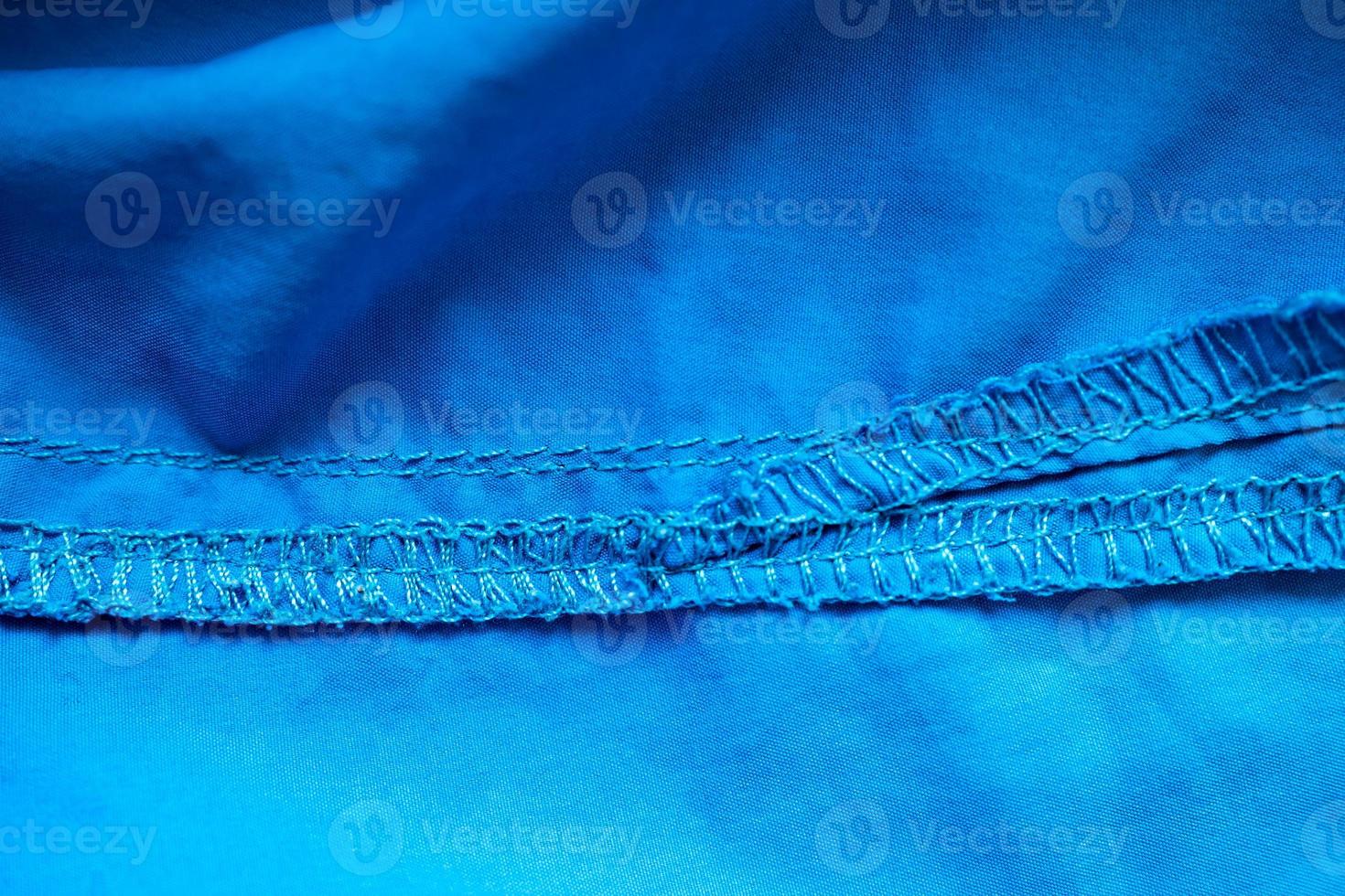 Overlock seam on blue fabric. Textured cloth background. Place for text. Flatley. photo