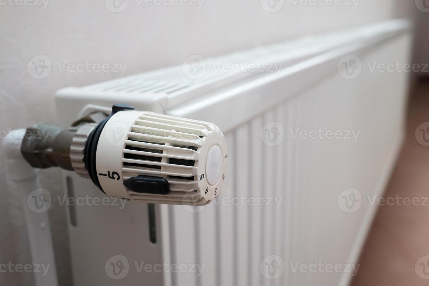 Radiator with thermostat and the ability to turn the knob and reduce the heating temperature. Concept of crisis and increase in heating costs. photo