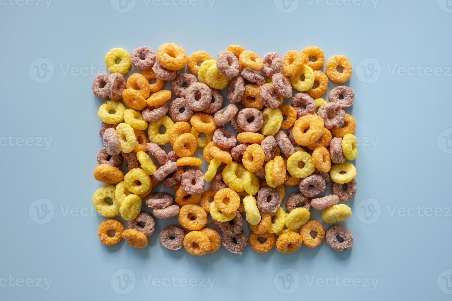 Dry breakfast from corn rings in the form of a frame on a blue background. Place for text. Flatley. photo