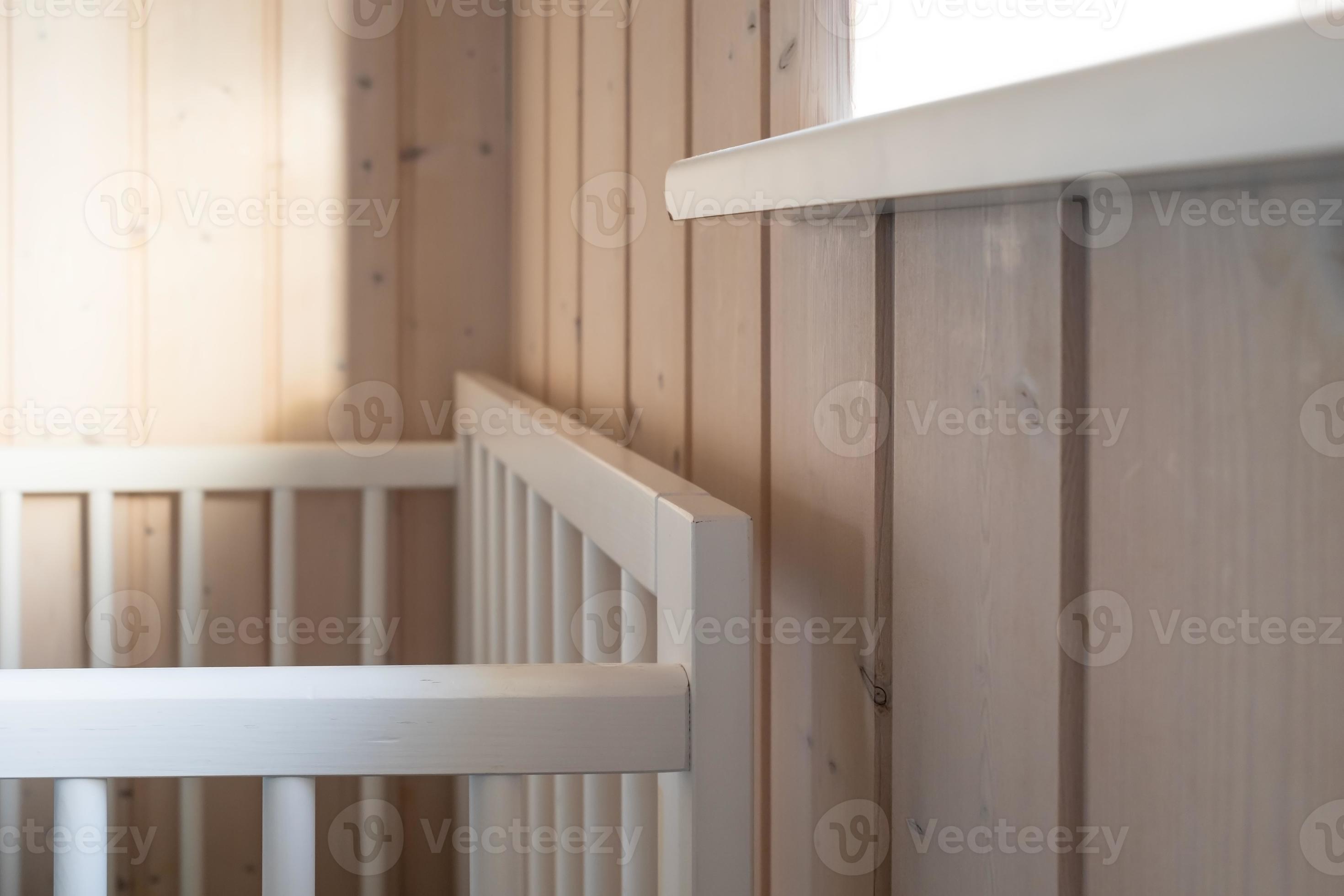 Room with a safe baby cot, wooden walls and a window through which