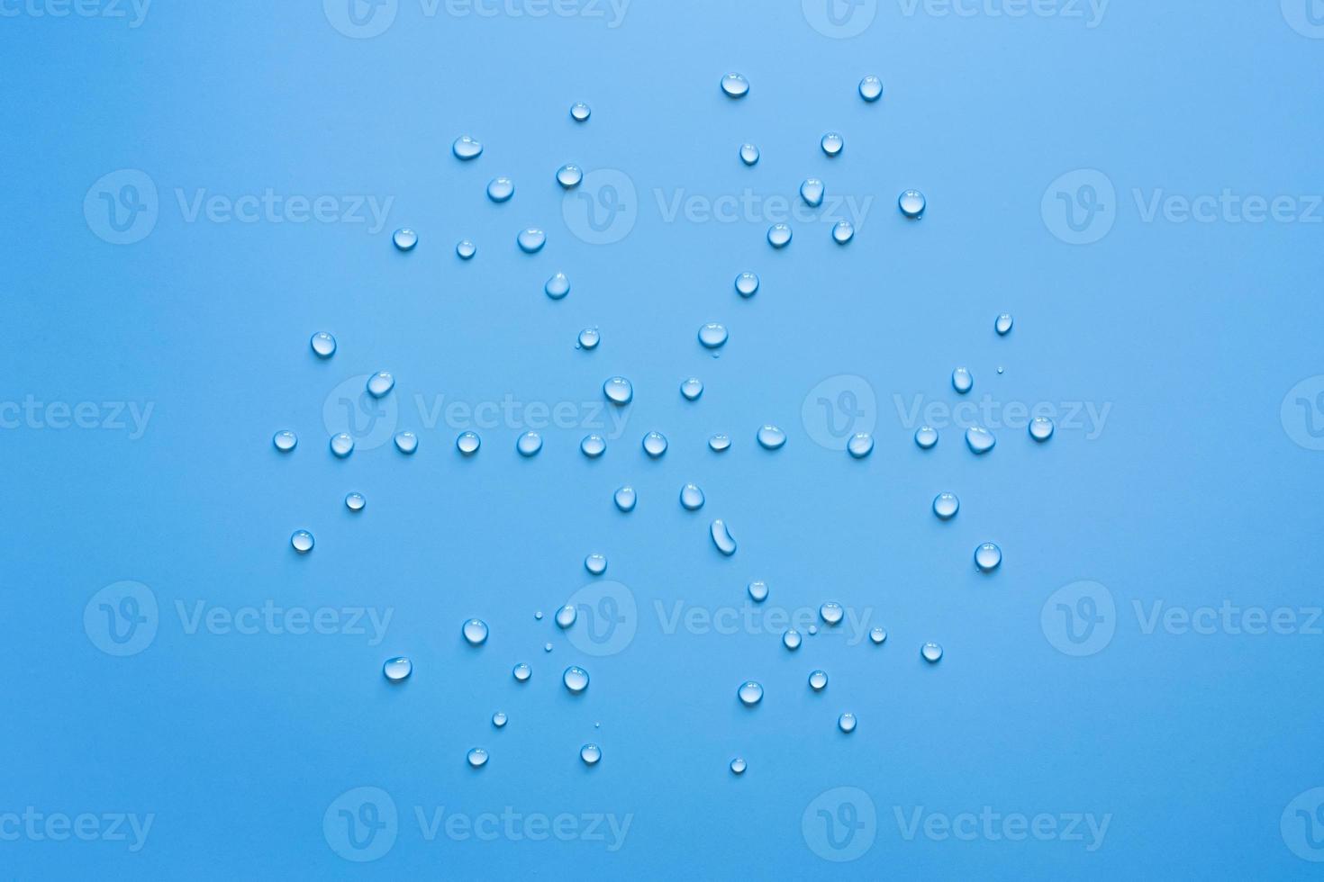Snowflake from water drops on a blue background. Concept of thaw and snow melt. Copy space. Flat lay. Top view. photo