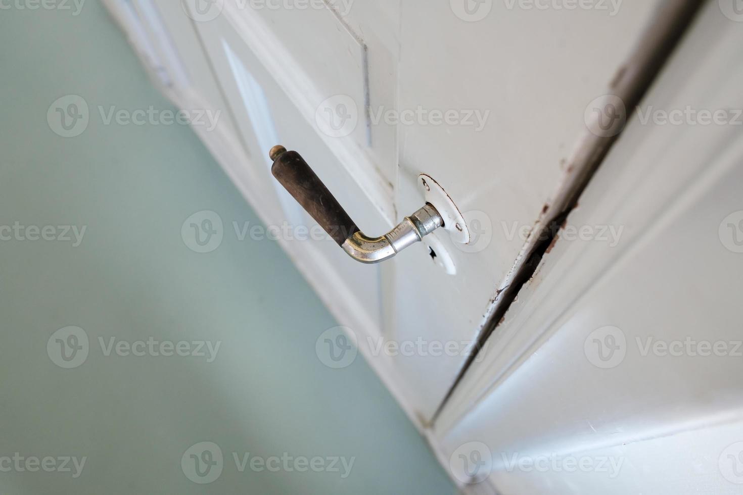 Old doorknob on a white wooden door, indoors. Close-up. Top view. photo