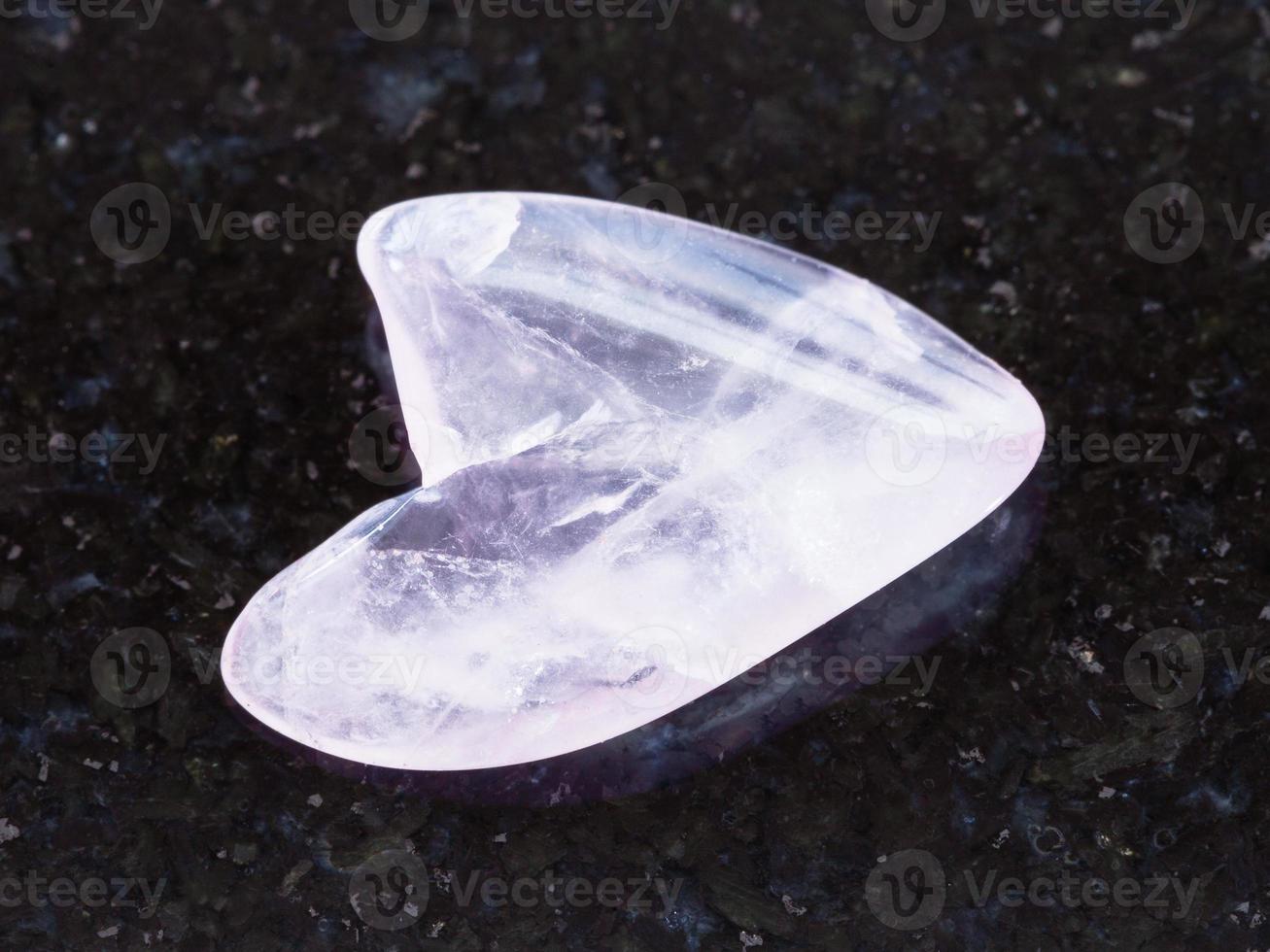 polished rose quartz stone in heart shape on dark photo
