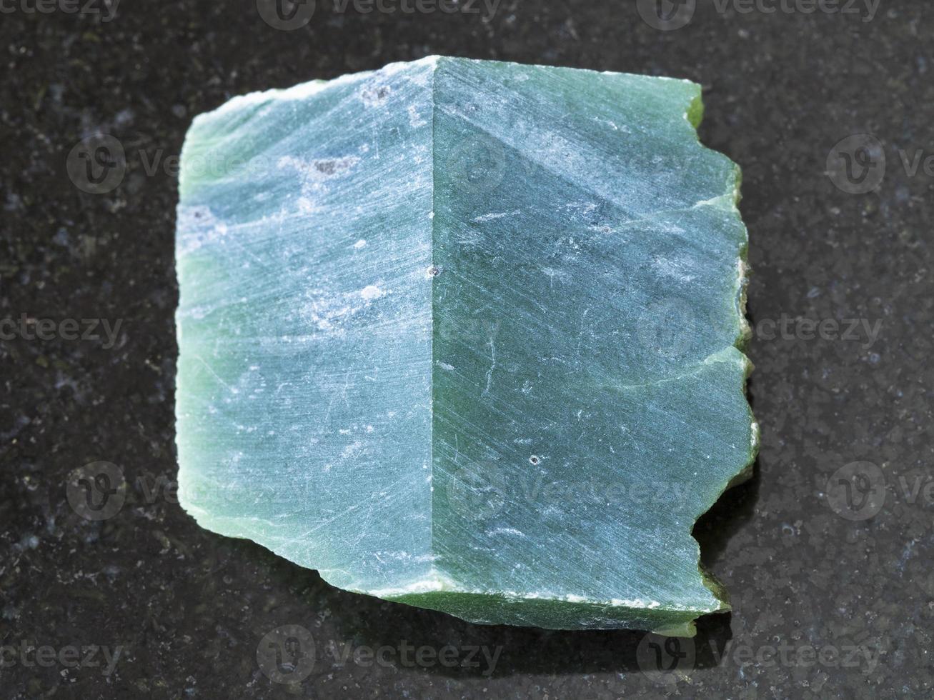 rough nephrite stone slab on dark background photo