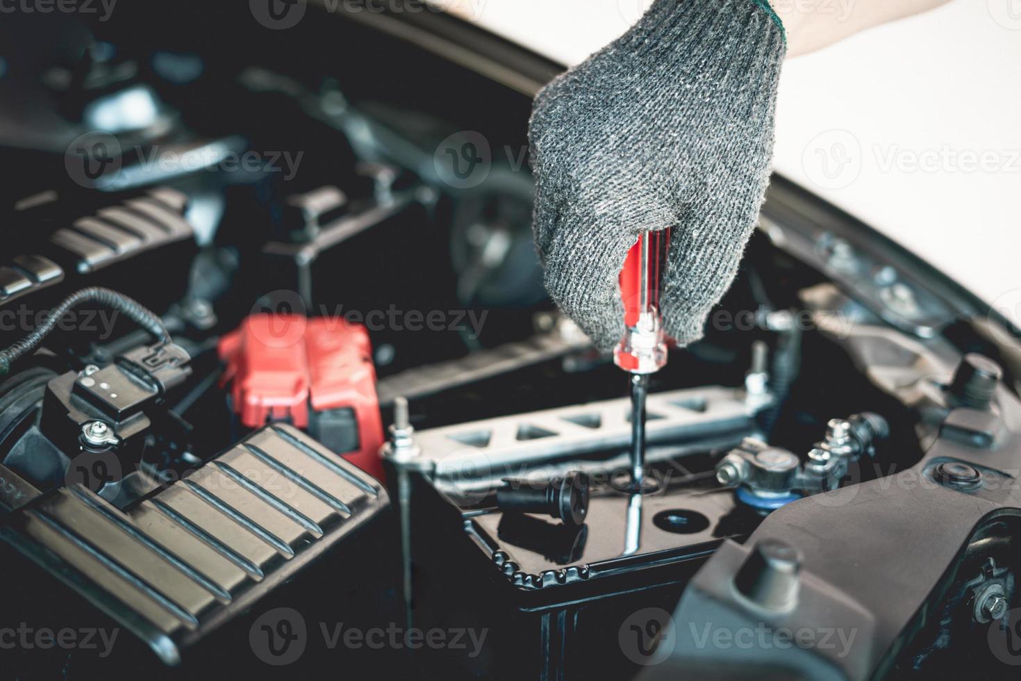 Close up hand a man wear glove use screwdriver open a cap battery for add distilled , maintenance and inspections for extended service life battery of car photo