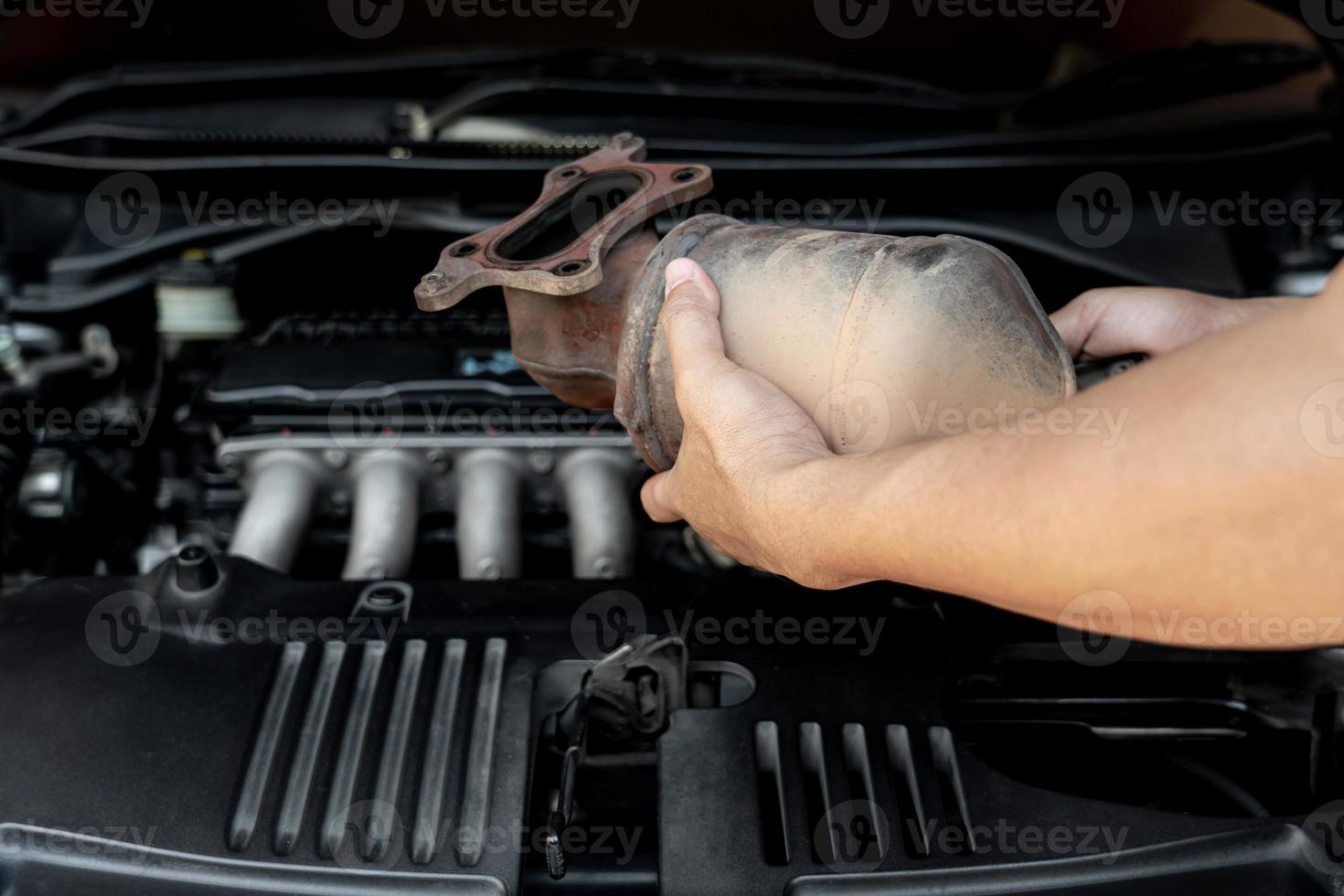 Close up old catalytic converter in hand Technician remove from engine gasoline car dust clogged condition on filter in service concept photo