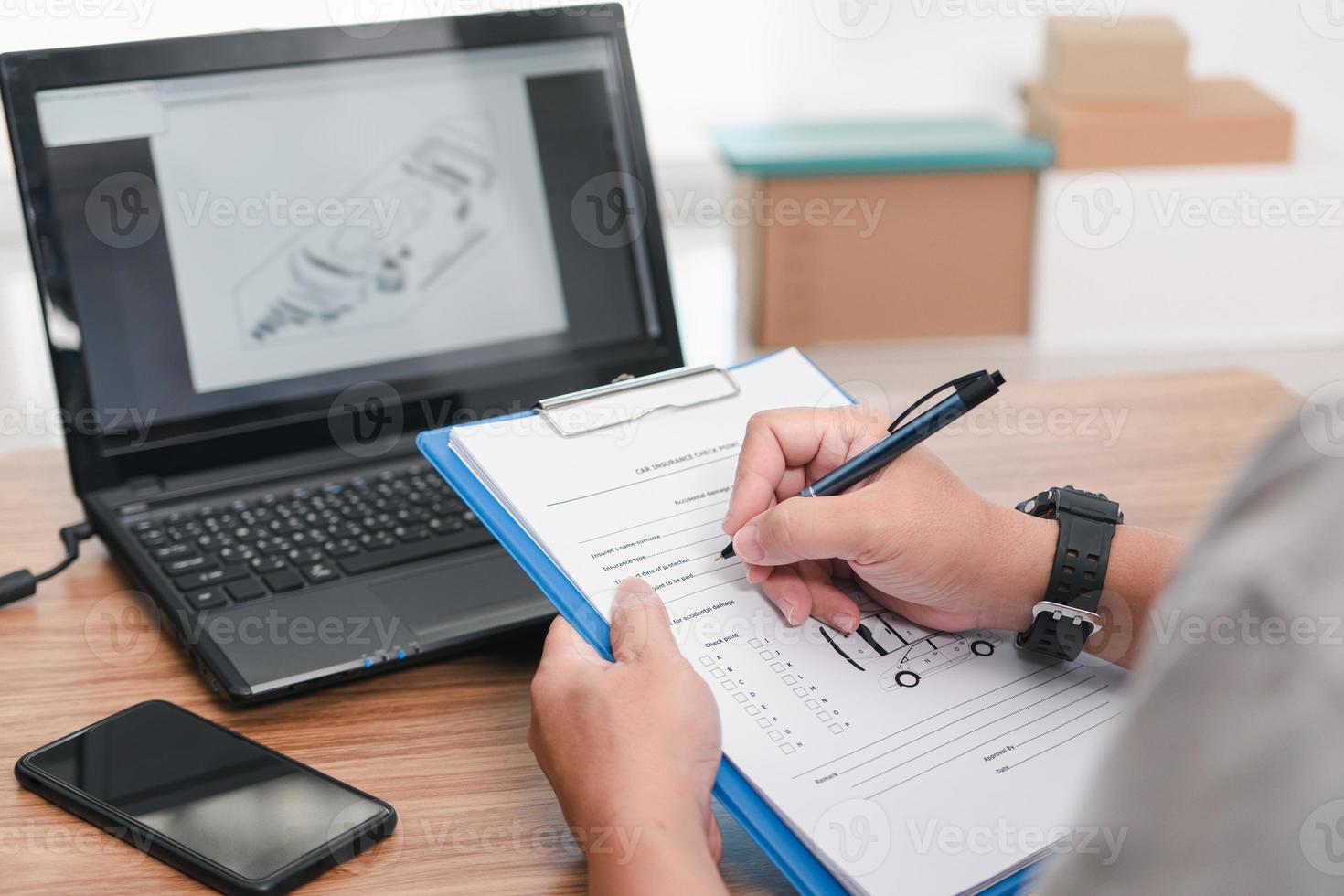 Car service staff use a pen check list in document with spare parts in stock on and check to assess the price of the insurance notification , Car insurance business concept photo