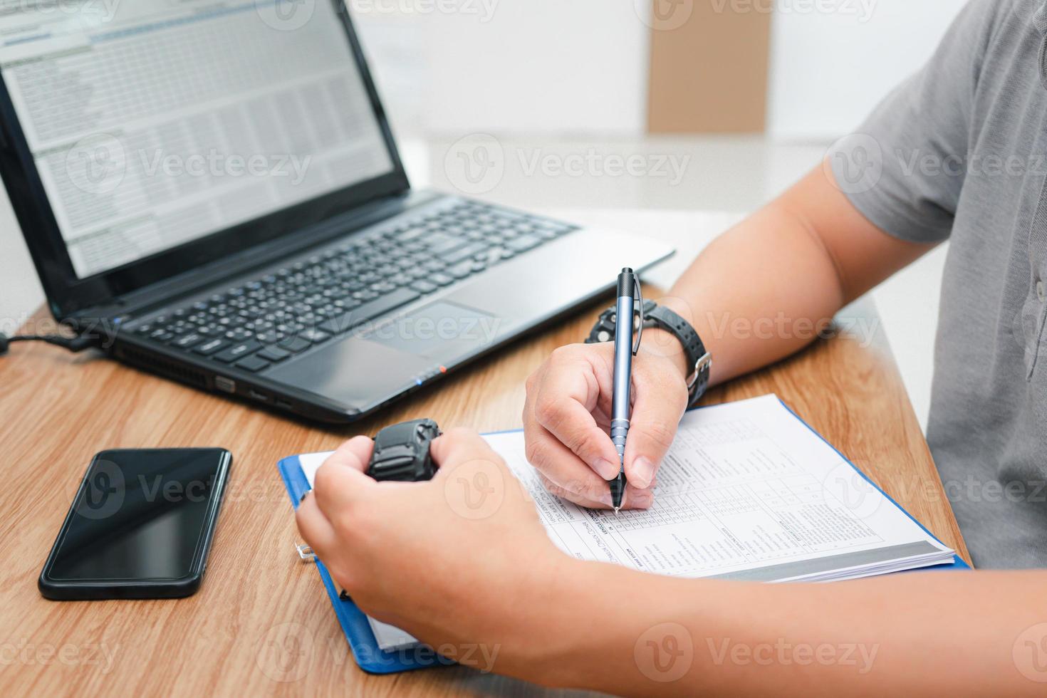 Business car service concept , a man use pen write on document file about the cost of repairing the car from the price of spare parts that must be replaced from stock and hold toy car in hand photo