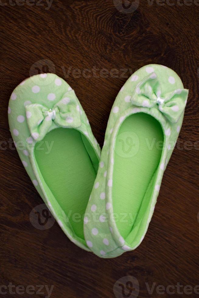 Female home green soft slippers on floor background photo