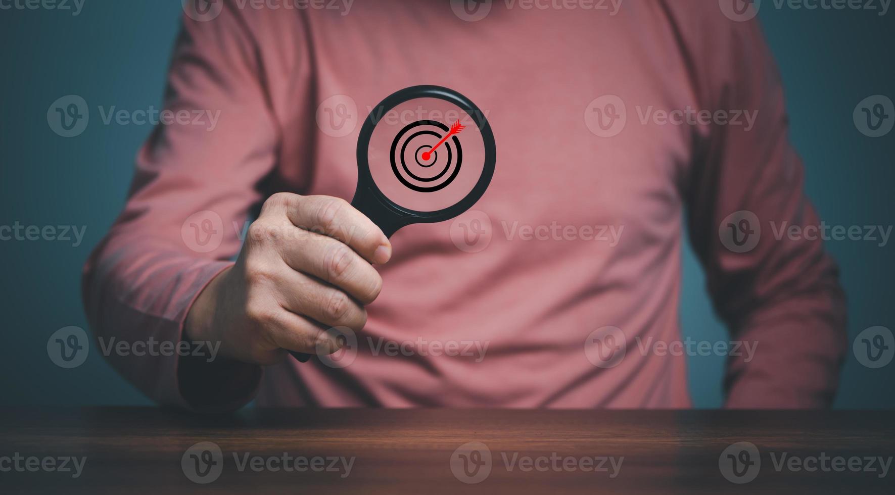 Target  inside magnifier glass for focus business objective, hand of person holding magnifier glass with goal target, Search, goal, strategy, success. photo